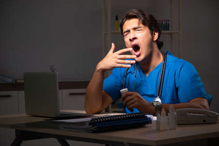 Young handsome doctor working night shift in hospitalの写真素材