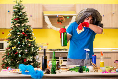 Young man cleaning kitchen after Christmas partyの写真素材