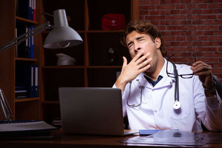 Young handsome doctor working night time at the hospitalの写真素材
