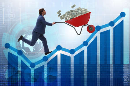 Businessman pushing wheelbarrow full of dollar moneyの写真素材