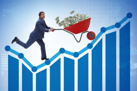 Businessman pushing wheelbarrow full of dollar moneyの写真素材