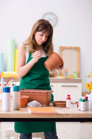 Young woman decorating pottery in workshopの写真素材