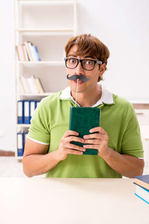 Student with fake moustache reading bookの写真素材