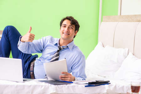Businessman working overtime in hotel roomの写真素材