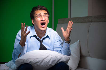 Young businessman under stress in the bedroom at nightの写真素材