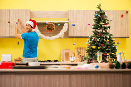 Young man celebrating Christmas in kitchenの写真素材