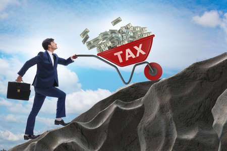 Businessman pushing tax wheelbarrow uphillの写真素材