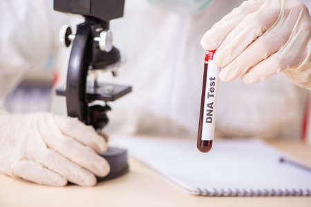 Young handsome lab assistant testing blood samples in hospitalの写真素材