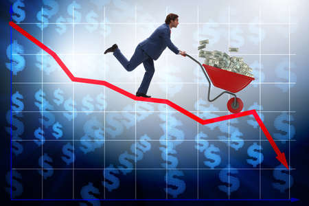 Businessman pushing money wheelbarrow down the chartの写真素材