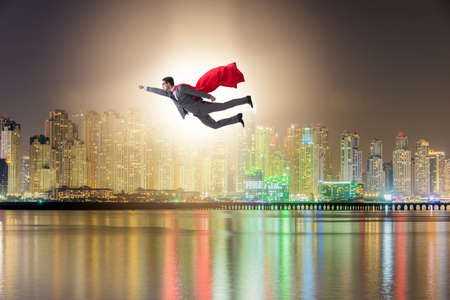 Superhero businessman flying over the cityの写真素材