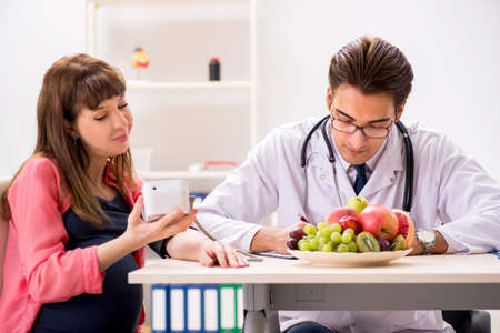 Pregnant woman visiting doctor discussing healthy dietの写真素材