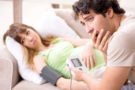 Husband checking pregnant wifes blood pressureの写真素材