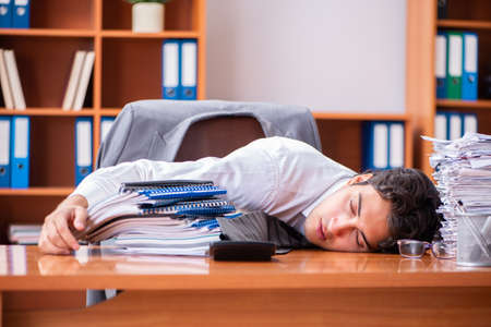 Young handsome businessman unhappy with excessive workの写真素材