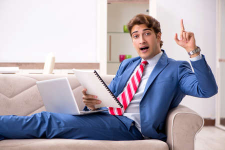 Young businessman working at home sitting on the sofaの写真素材
