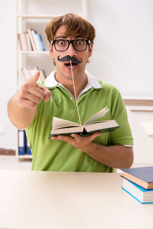 Student with fake moustache reading bookの写真素材
