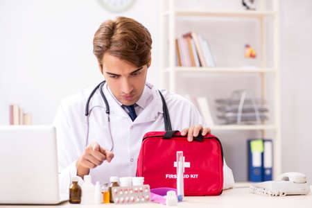 Young doctor with first aid kit in hospitalの写真素材