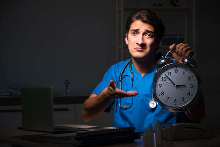 Young handsome doctor working night shift in hospitalの写真素材