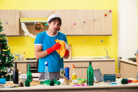 Young man cleaning kitchen after Christmas partyの写真素材