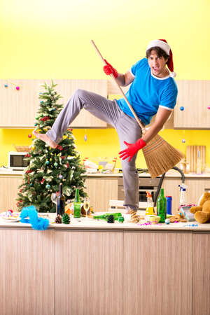 Young man cleaning kitchen after Christmas partyの写真素材