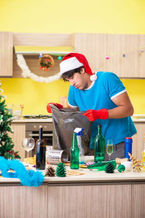 Young man cleaning kitchen after Christmas partyの写真素材