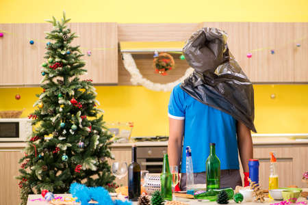 Young man cleaning kitchen after Christmas partyの写真素材
