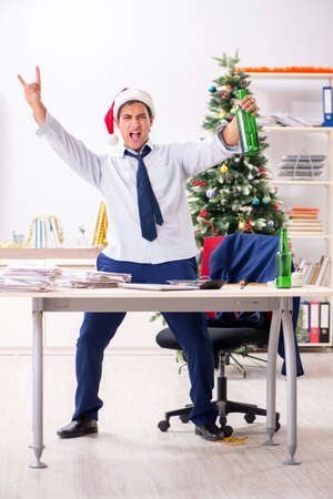 Young handsome employee celebrating Christmas at workplaceの写真素材