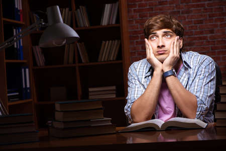Young handsome student preparing for exams at nightの写真素材