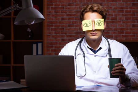 Young handsome doctor working night time at the hospitalの写真素材