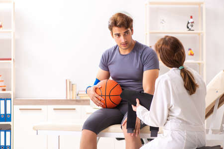 Handsome basketball player visiting female doctor traumatologistの写真素材