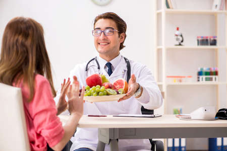 Pregnant woman visiting doctor discussing healthy dietの写真素材
