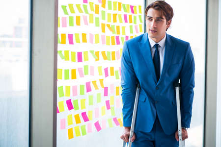 Young handsome man with crutches in conflicting priorities conceの写真素材
