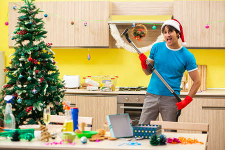 Young man cleaning kitchen after Christmas partyの写真素材
