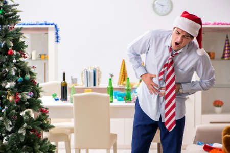 Young handsome employee celebrating Christmas at workplaceの写真素材