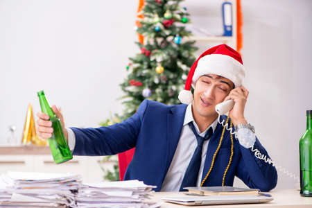 Young handsome employee celebrating Christmas at workplaceの写真素材
