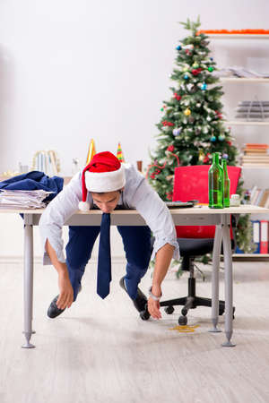 Young handsome employee celebrating Christmas at workplaceの写真素材