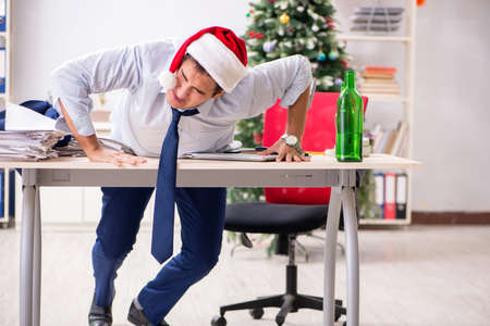 Young handsome employee celebrating Christmas at workplaceの写真素材