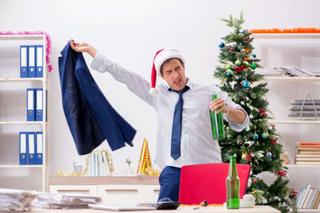 Young handsome employee celebrating Christmas at workplaceの写真素材