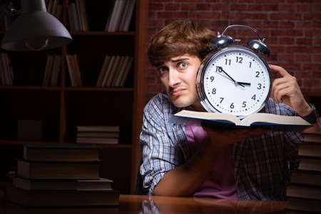 Young handsome student preparing for exams at nightの写真素材