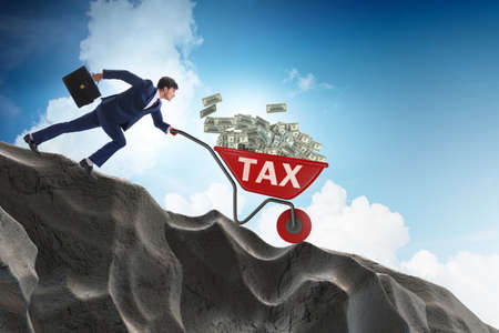 Businessman pushing wheelbarrow with tax moneyの写真素材