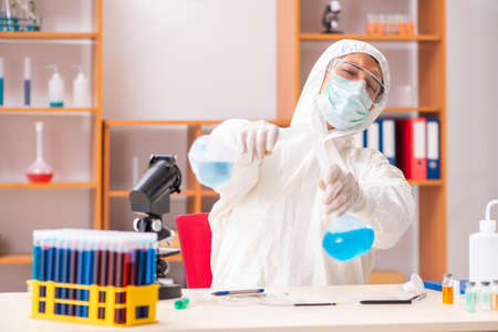 Young biochemist wearing protective suit working in the lab