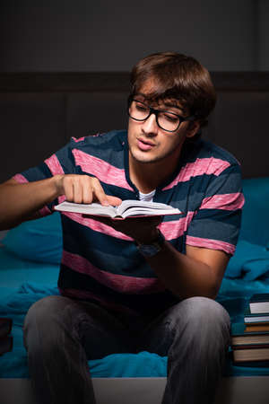Young handsome student preparing for exams at nightの写真素材