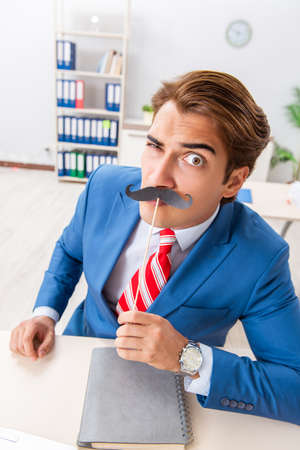 Funny bisinessman with fake moustache in the officeの写真素材
