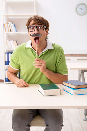 Student with fake moustache reading bookの写真素材