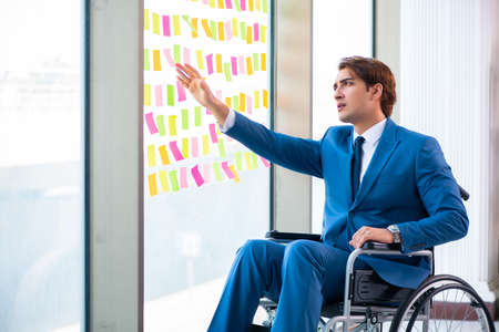 Young handsome man in wheelchair with many conflicting prioritieの写真素材