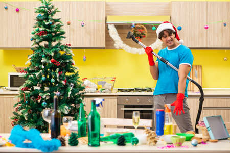 Young man cleaning kitchen after Christmas partyの写真素材