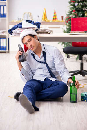 Young handsome employee celebrating Christmas at workplaceの写真素材