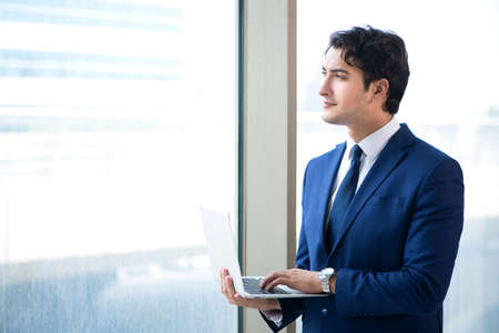 Young handsome businessman standing at the windowの写真素材