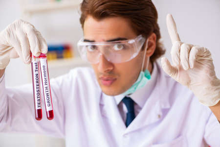 Young handsome lab assistant testing blood samples in hospital