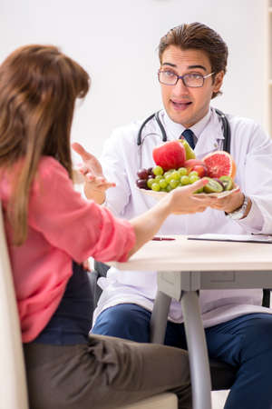 Pregnant woman visiting doctor discussing healthy dietの写真素材