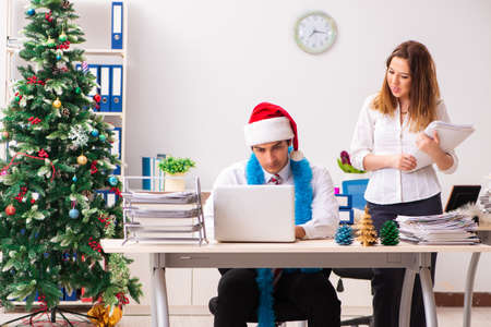 Man and woman working at the office on Cristmass eveの写真素材